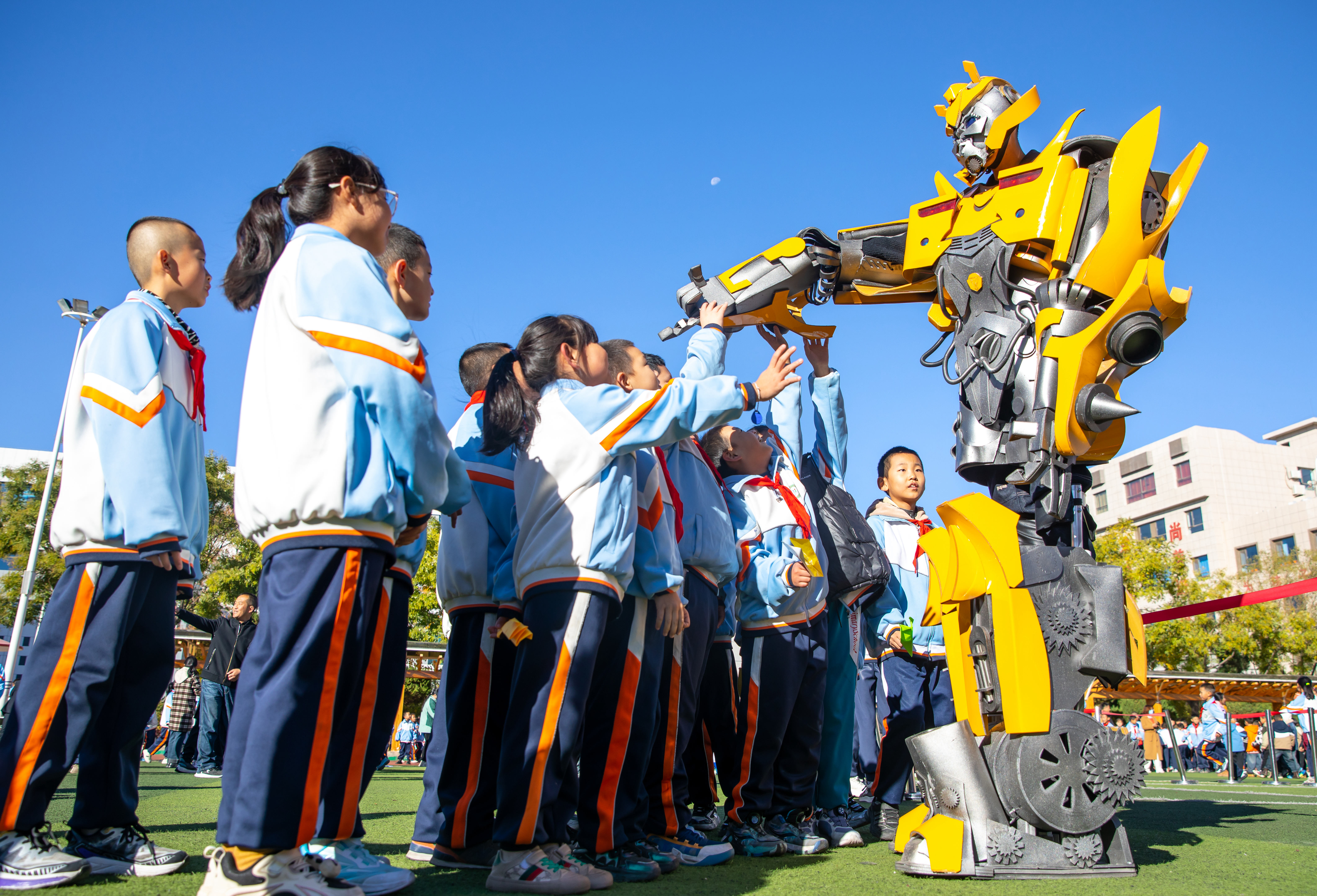 2024年10月22日，在甘肅省張掖市甘州區(qū)北街街小學科技大篷車嘉年華活動上，學生與“大黃蜂”機器人互動。楊瀟 攝.jpg