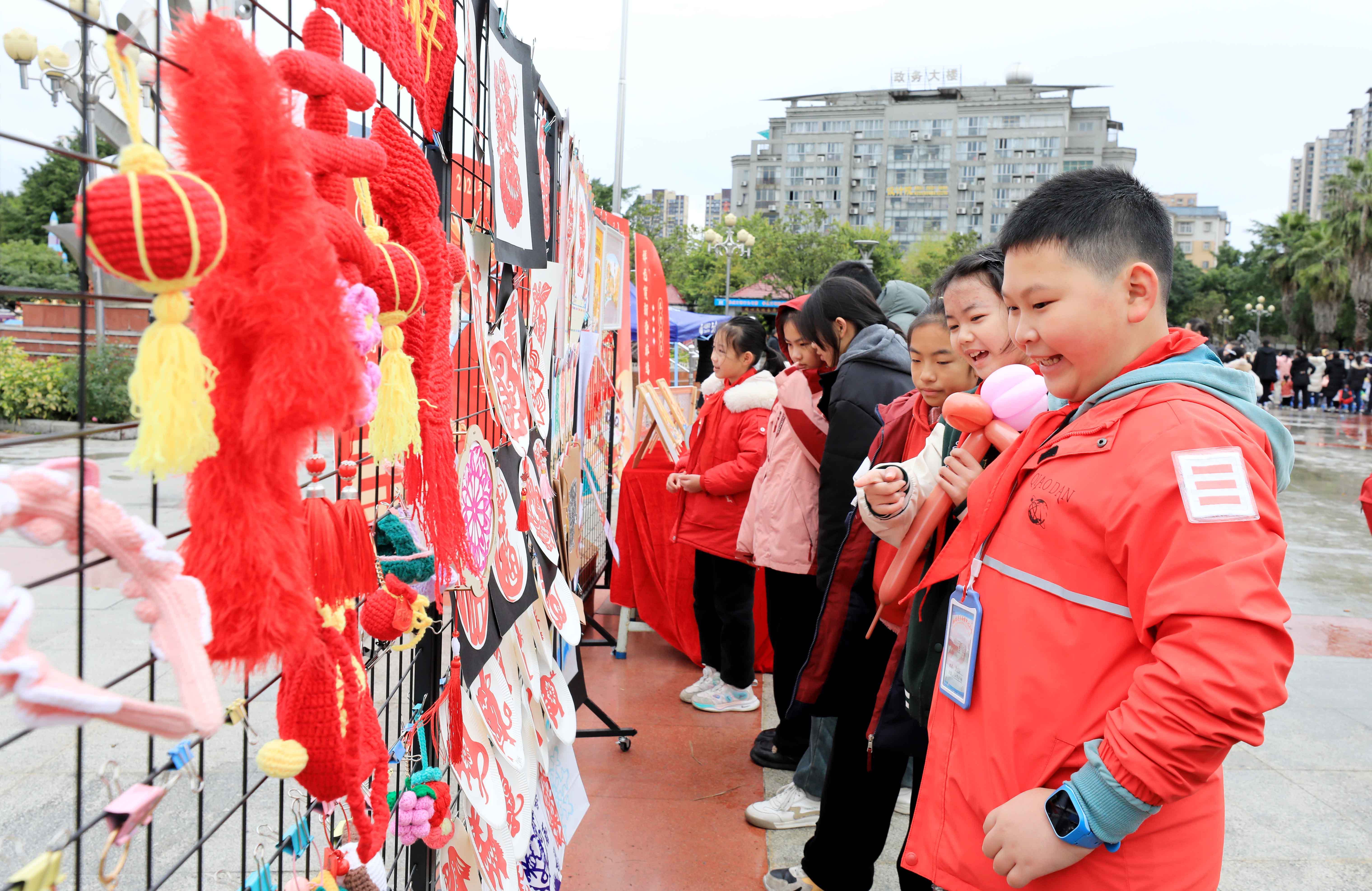 圖7：1月20日，在廣西柳州市融安縣長安廣場，學(xué)生在非遺集市上選購作品。（譚凱興 攝）.JPG